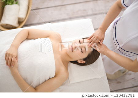 Young woman receiving a massage from an esthetician Young woman receiving a massage from an esthetician 120432791