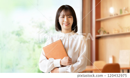 Smiling young woman/businesswoman holding a file 120432975