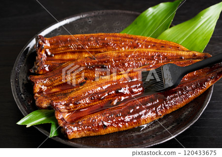 將醬汁塗在烤好的鰻魚上 將醬汁塗在烤好的鰻魚上 120433675