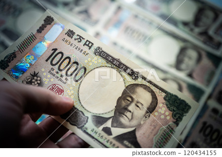 A man is holding a 10,000 yen bill A man is holding a 10,000 yen bill 120434155