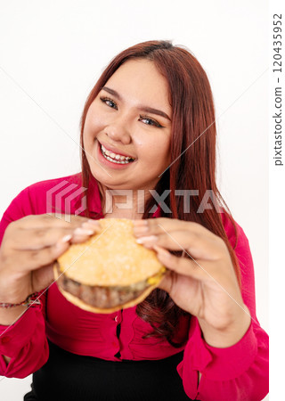 A Joyful Young Woman Happily Enjoying a Delicious Hamburger with Enthusiasm 120435952