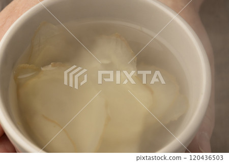 手裡拿著一個裝滿薑茶的杯子 120436503