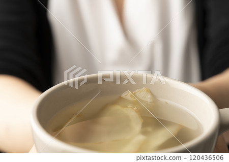 手裡拿著一個裝滿薑茶的杯子 手裡拿著一個裝滿薑茶的杯子 120436506