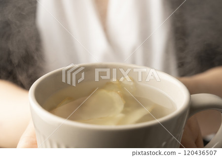 手裡拿著一個裝滿薑茶的杯子 手裡拿著一個裝滿薑茶的杯子 120436507
