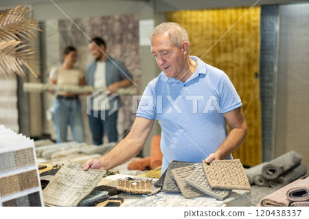 Senior man look at samples of carpet fabrics, small pieces of floor pile coverings. Senior man look at samples of carpet fabrics, small pieces of floor pile coverings. 120438337