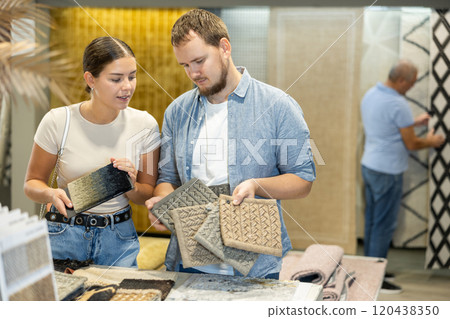 Couple man and woman choosing carpet samples in store Couple man and woman choosing carpet samples in store 120438350