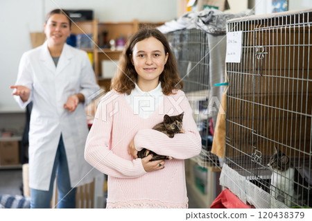 Preteen girl standing in animal shelter with kitten in hands Preteen girl standing in animal shelter with kitten in hands 120438379