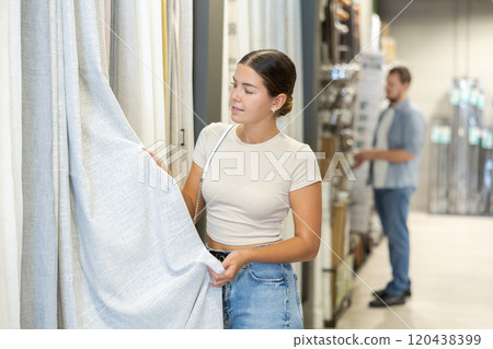 Female customer choose beautiful curtains for windows of their new home together 120438399