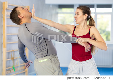 Young girl practicing self-defense techniques in pair with middle-aged man 120438404