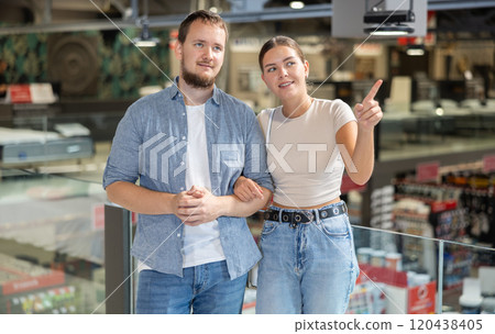 Couple looking for something in furniture store, searching for perfect item to complete living space Couple looking for something in furniture store, searching for perfect item to complete living space 120438405