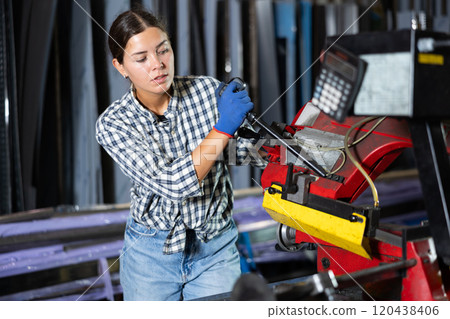 Young woman cuts profile pipe on machine Young woman cuts profile pipe on machine 120438406