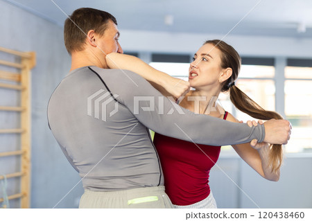 Self-defense training - woman practicing blows to the head of male attacker 120438460