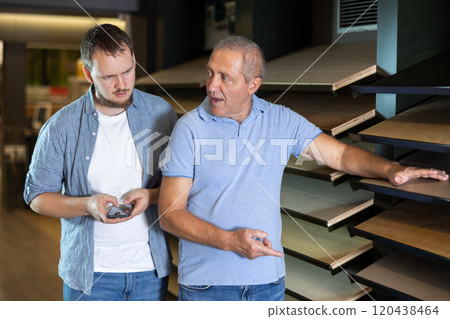Mature man and guy son carefully examine wooden finishing material 120438464