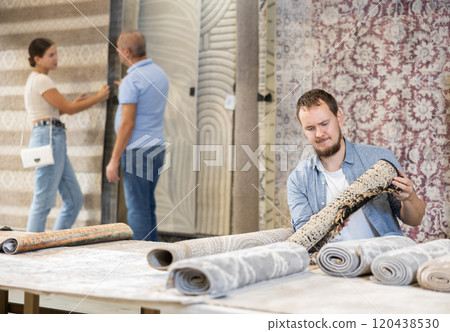 Young man choosing carpet in building store 120438530