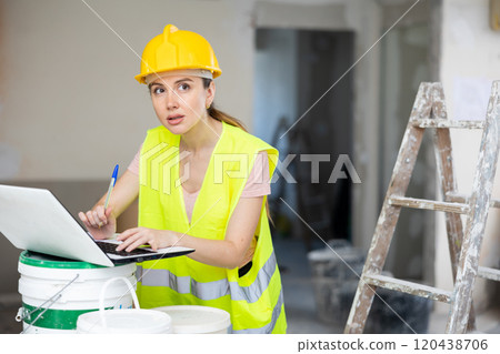 Woman architect using laptop at renovating apartment 120438706