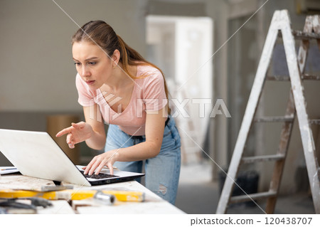 Woman with laptop at house being renovated Woman with laptop at house being renovated 120438707