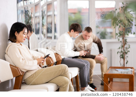 Young woman sitting in line with phone 120438746