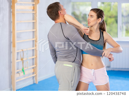 Young girl practicing self-defense techniques in pair with middle-aged man 120438748