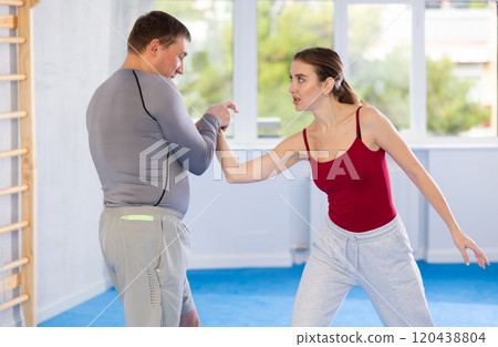 Young girl and middle-aged man practicing arm twist technique during self-defense courses 120438804
