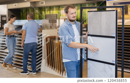 Man looking to buy floor ceramic tiles in materials section of store 120438855