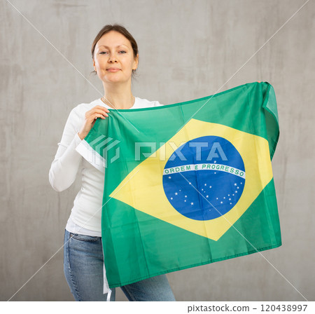 Attractive female football fan holding Brazilian flag 120438997