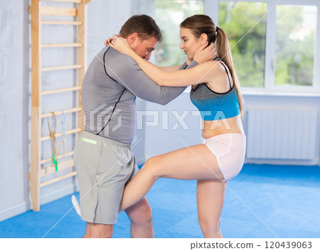 Young girl practicing feet kick method of self-defense in pair with middle-aged man Young girl practicing feet kick method of self-defense in pair with middle-aged man 120439063