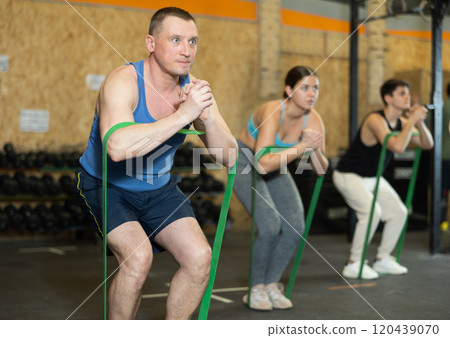 Focused man exercising with resistance band loop in gym 120439070