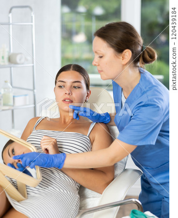 Woman cosmetologist examines patients nasolabial area after lifting procedure and palpates lips mouth 120439184