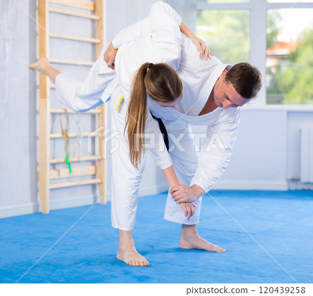 Coach teaches young woman techniques for wrestling and throwing on sports mats during judo training 120439258