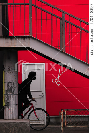 一名男子騎著自行車穿過紅牆並在人行天橋下 120440390