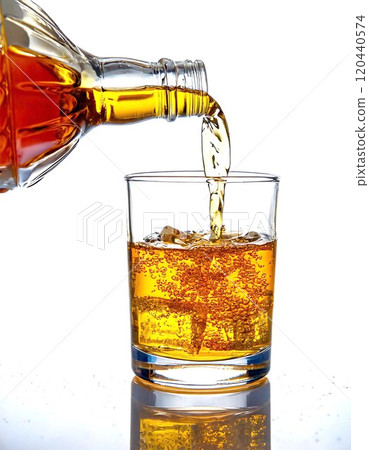 A refreshing beverage being poured into a glass filled with ice cubes. 120440574