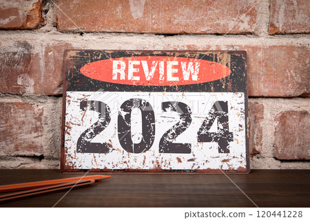 Review 2024 Concept. Metal sign with inscription on wooden texture office desk 120441228
