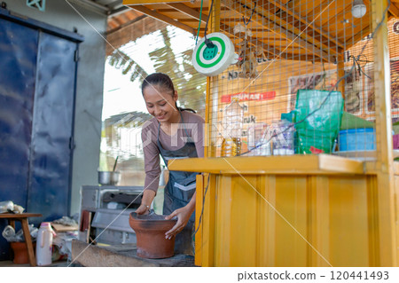 A woman is potting clay in a bright and vibrant artisan studio environment A woman is potting clay in a bright and vibrant artisan studio environment 120441493