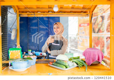Smiling Vendor at a Colorful Food Stall Surrounded by Fresh Vegetables Smiling Vendor at a Colorful Food Stall Surrounded by Fresh Vegetables 120441510