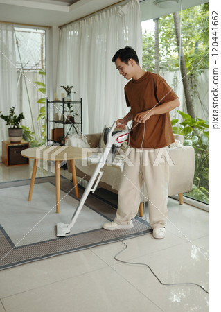 Man Vacuuming Carpet in Bright Living Room Man Vacuuming Carpet in Bright Living Room 120441662