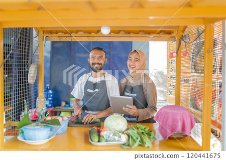 Cheerful and friendly Food Vendors working in a Cozy Outdoor Kitchen Stall Cheerful and friendly Food Vendors working in a Cozy Outdoor Kitchen Stall 120441675
