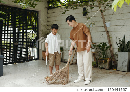 Teaching Young Boy Sweeping Floor in Backyard 120441767