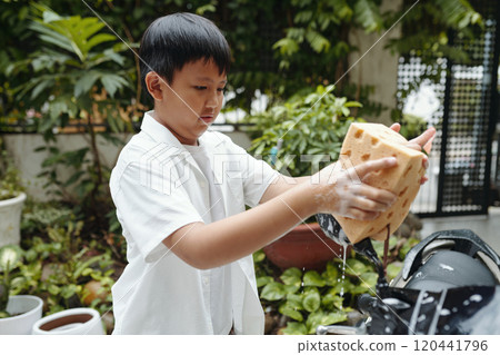Young Boy Washing Car Using Large Sponge Outdoors 120441796
