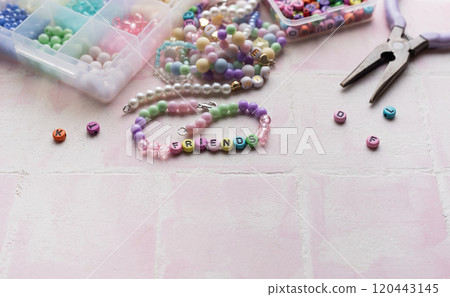 Colorful beads and pliers arranged on pink tile for jewelry making Colorful beads and pliers arranged on pink tile for jewelry making 120443145