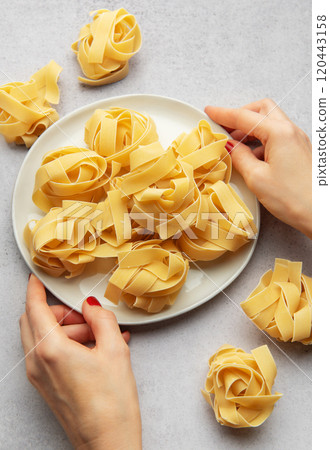Chef placing uncooked pasta on white plate for italian cuisine Chef placing uncooked pasta on white plate for italian cuisine 120443158