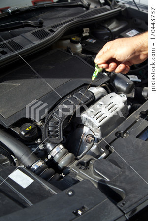 Hands of a Caucasian car mechanic performing a general check of the car's engine compartment Hands of a Caucasian car mechanic performing a general check of the car's engine compartment 120443737