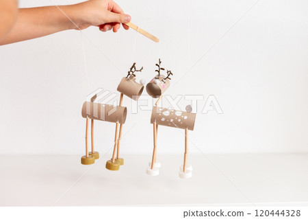controlling DIY reindeer puppets made from cardboard tubes and bottle caps. Christmas and winter holiday craft concept. recycle paper, 120444328