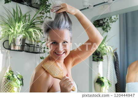 Portrait funny mature gray haired woman at light bathroom with hairbrush closeup 120444947