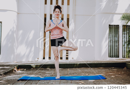 Girl doing yoga vrikshasana or tree pose outdoors. Young woman doing vrikshasana yoga outdoors. Relaxation and vitality yoga concept 120445345