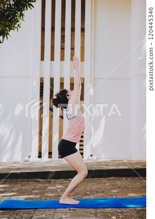 Young woman doing yoga chair pose outdoors. Girl doing yoga UTKATASANA or chair pose outdoors. Ashtanga Vinyasa yoga concept Young woman doing yoga chair pose outdoors. Girl doing yoga UTKATASANA or chair pose outdoors. Ashtanga Vinyasa yoga concept 120445346