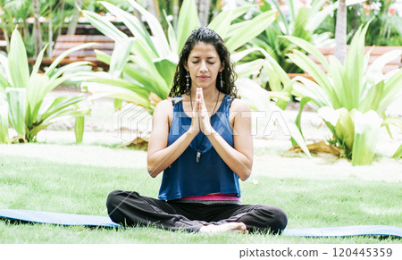 A girl sitting doing meditation yoga outdoors, Woman doing yoga outdoors, a young woman doing yoga with closed eyes. A girl sitting doing meditation yoga outdoors, Woman doing yoga outdoors, a young woman doing yoga with closed eyes. 120445359