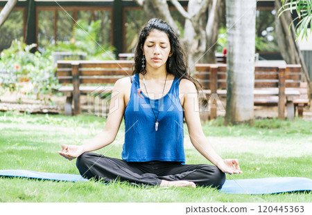 A girl sitting doing meditation yoga outdoors, Woman doing yoga outdoors, a young woman doing yoga with closed eyes. 120445363