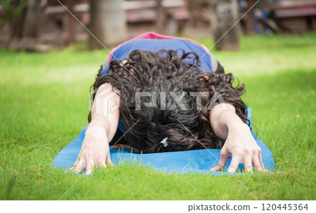 Close up of girl doing stretching yoga, girl doing bharata yoga, young woman doing stretching yoga outdoors 120445364