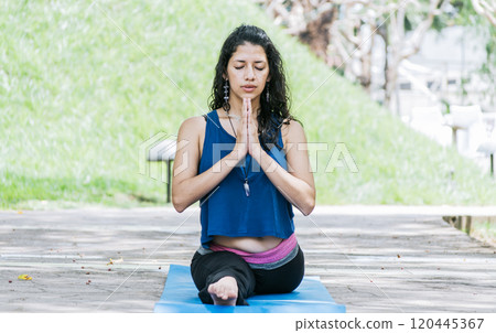 Girl sitting doing split meditation yoga outdoors, woman doing side split yoga outdoors, young woman doing side split yoga 120445367