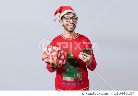 Handsome man in christmas hat holding gift and looking at phone, Guy in christmas hat holding gift box and smiling at smartphone, Christmas man holding gift box and telephone isolated Handsome man in christmas hat holding gift and looking at phone, Guy in christmas hat holding gift box and smiling at smartphone, Christmas man holding gift box and telephone isolated 120446194